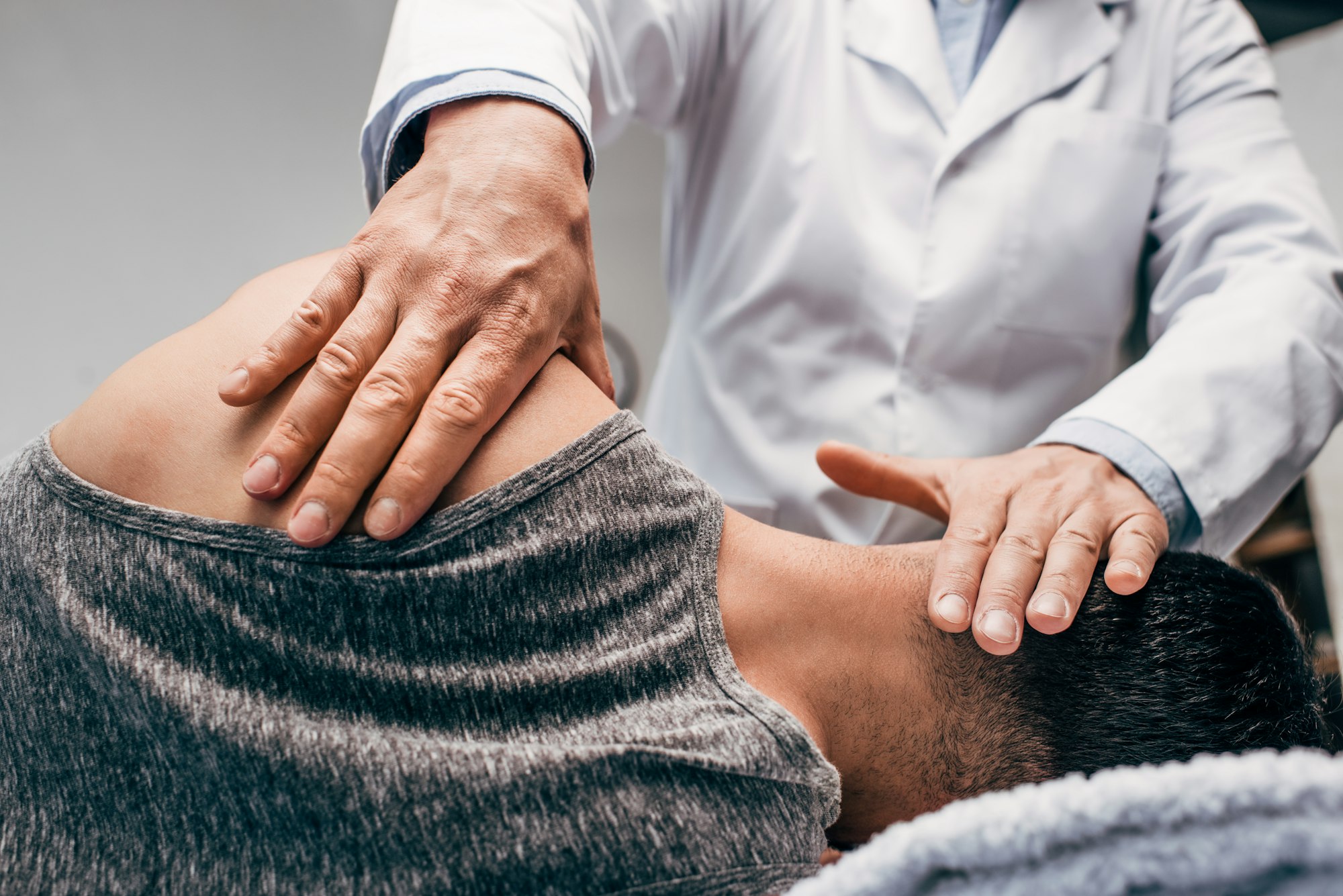 chiropractor in white coat massaging neck of man