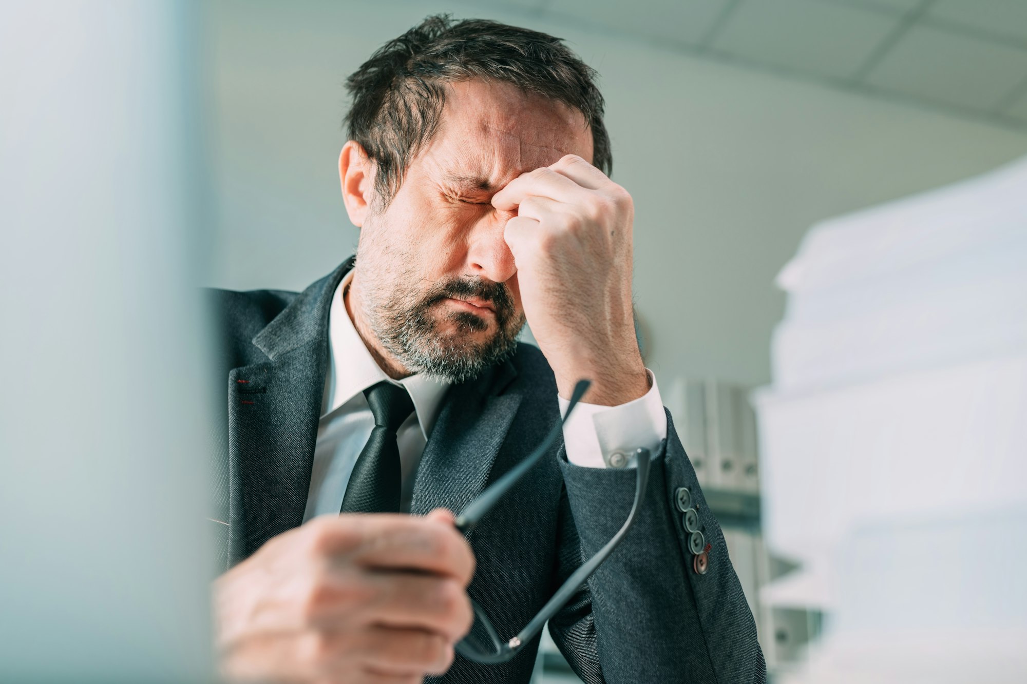 Migraines at work, businessman with severe painful headache symptoms