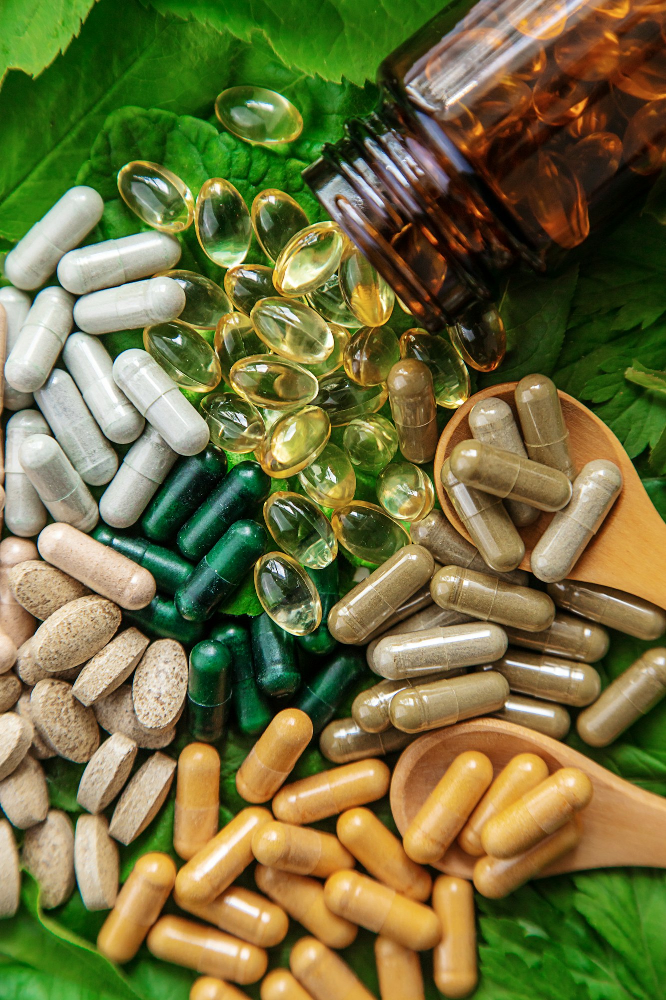 Capsules herb supplements on green leaves background. Selective focus.